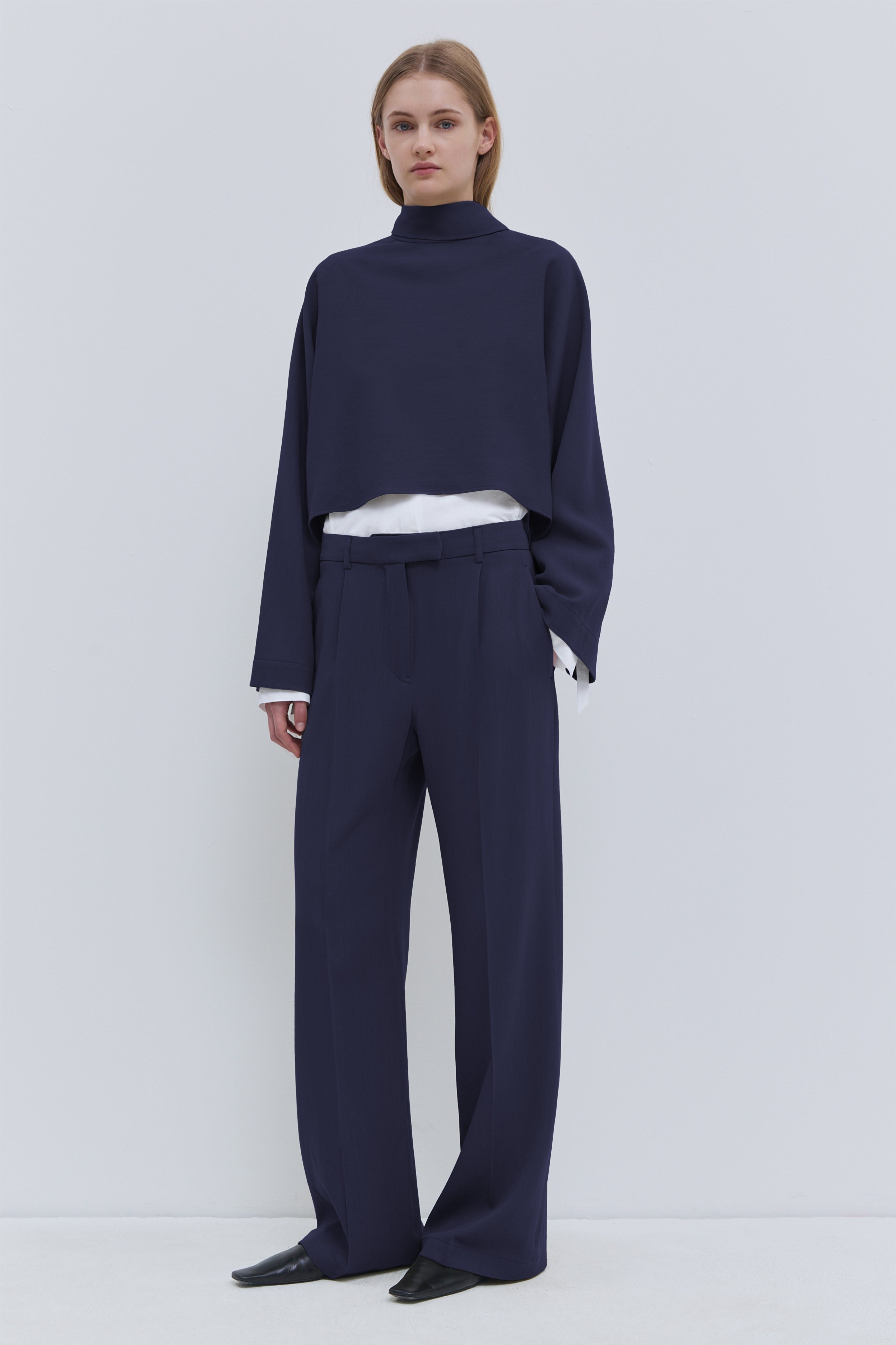 Tesos dark navy wool cropped top with asymmetrical scarf detail and long sleeves.