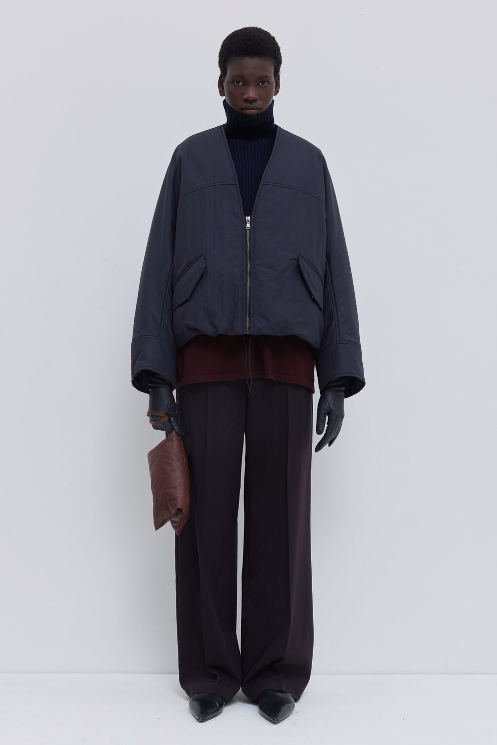 Navy oil Jelana padded jacket styled open over a ribbed turtleneck knit and wide-leg tailored trousers.