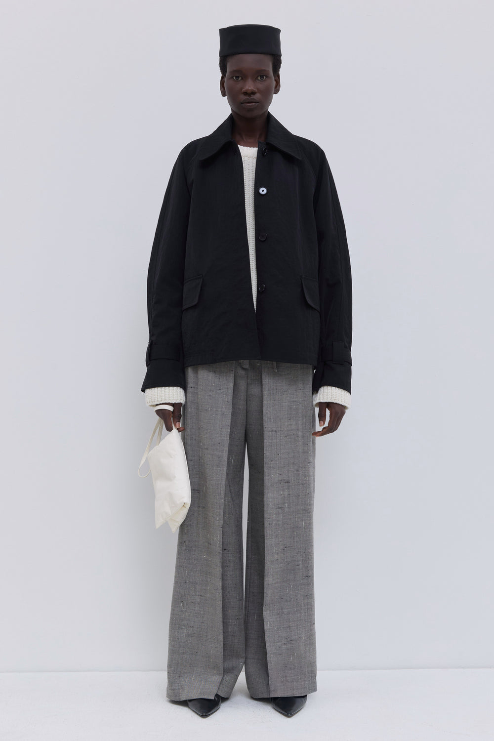Black raglan-sleeve jacket with a classic collar and oversized flap pockets.