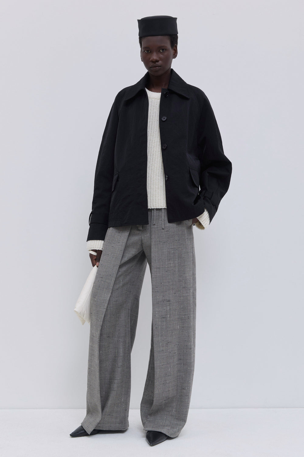 Back view of a black raglan-sleeve jacket with a clean, minimal silhouette.