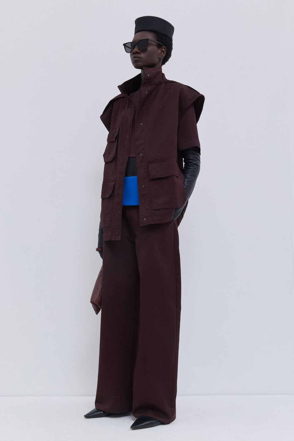 Plum sleeveless utility jacket in garment-dyed organic cotton featuring oversized shoulders, patch pockets and a stand collar.
