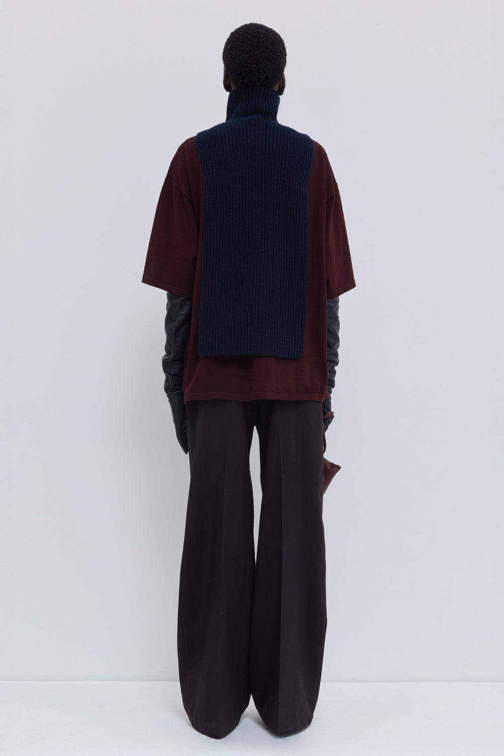 Back view of dark marine ribbed merino wool and cashmere knit bib with elongated silhouette and oversized turtleneck.