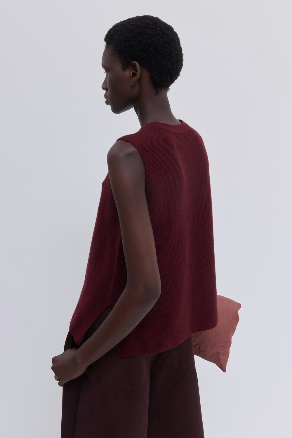 Luxury garnet sleeveless knit top with side slits and seamless construction.