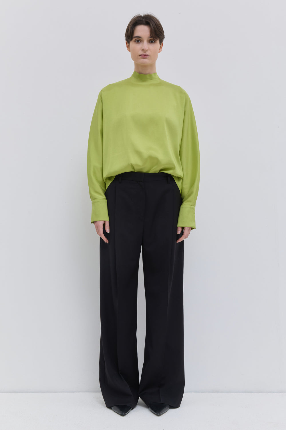 Model wearing black Italian wool wide-leg trousers with front crease and tailored fit by Christian Wijnants.