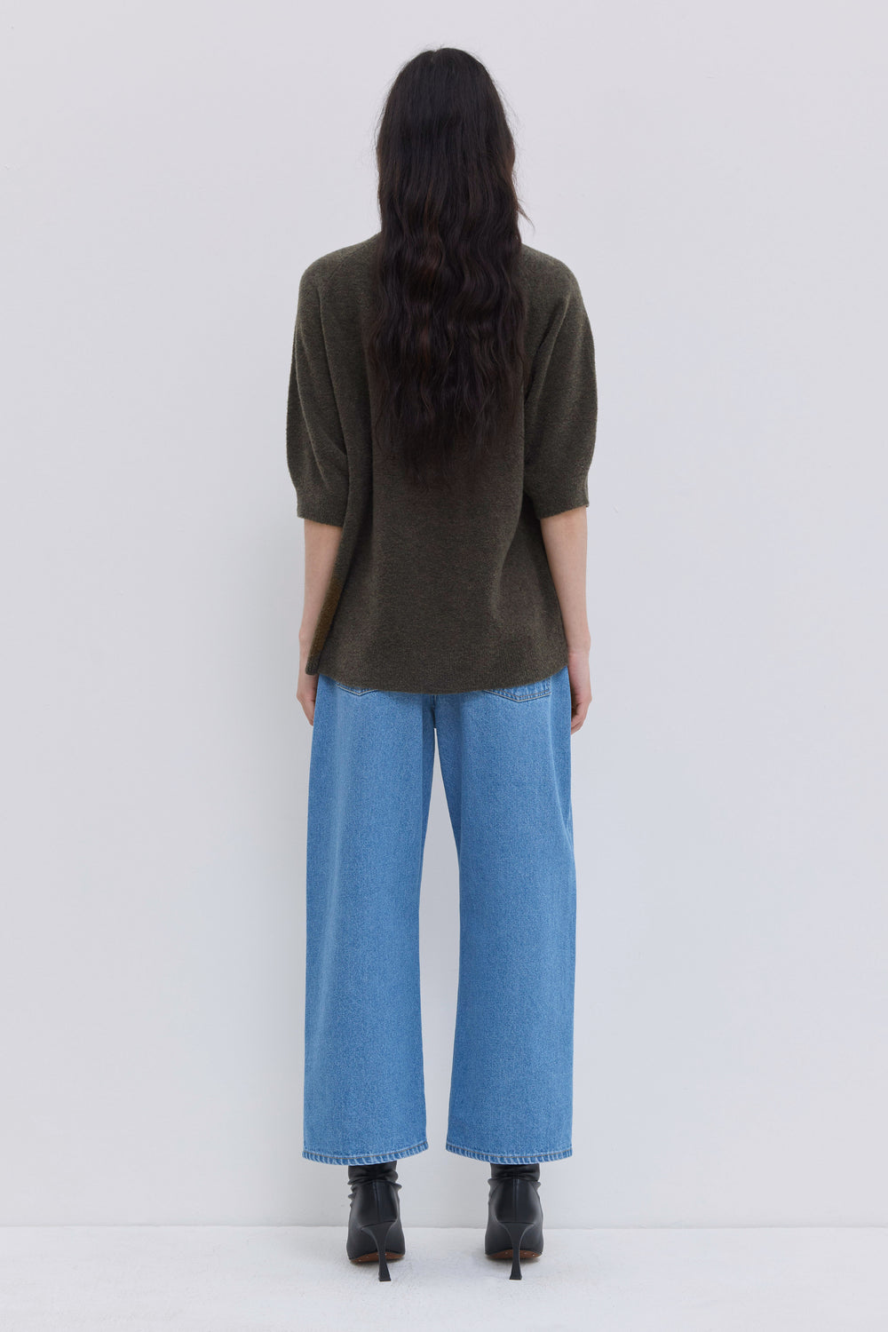 Back view of blue cropped denim pants with patch pockets.