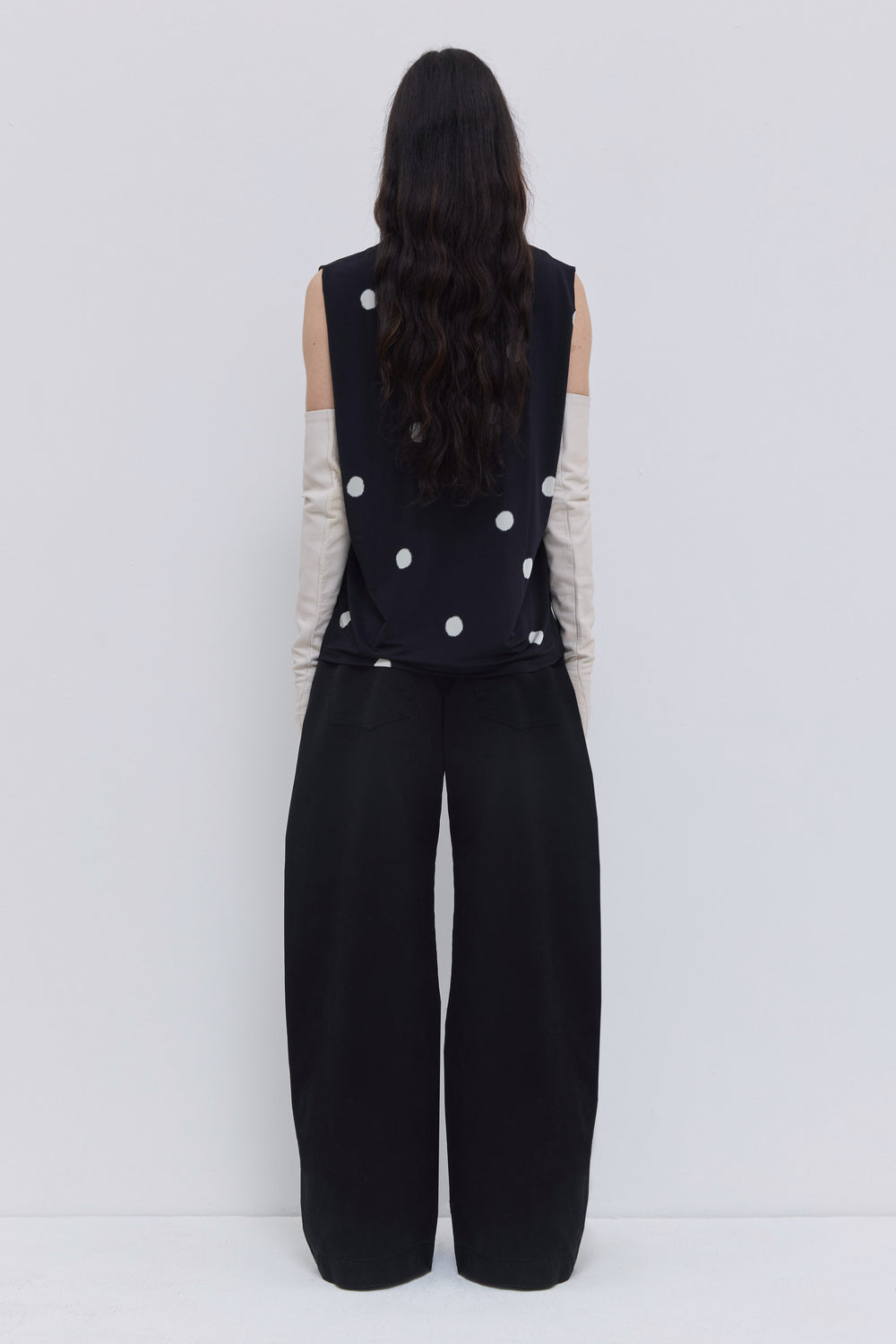 Back view of a black sleeveless top with large white polka dots, shoulder pleats and relaxed shape by Christian Wijnants.