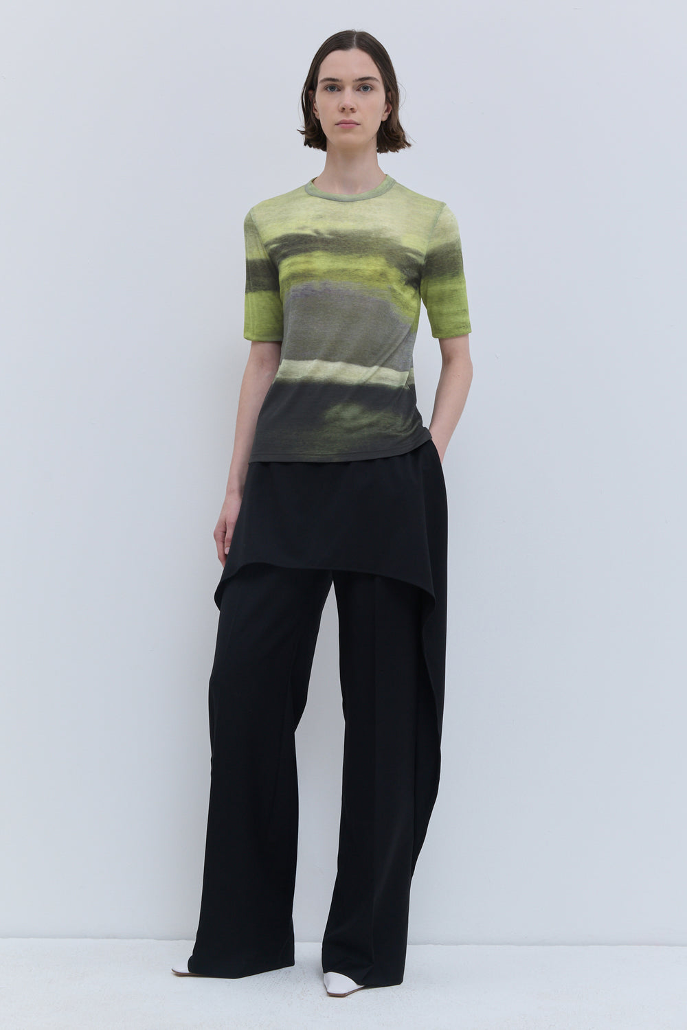 Model wearing the Tampi short-sleeve wool jersey top in Day Break print, featuring a close-fitting silhouette and abstract green landscape-inspired print.
