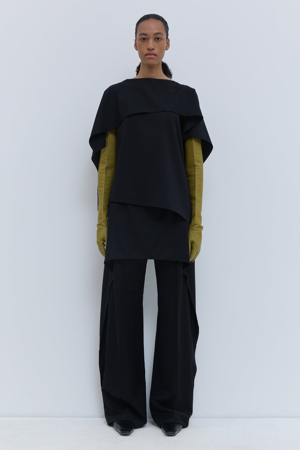 Black sleeveless virgin wool panel top with layered flap detail.
